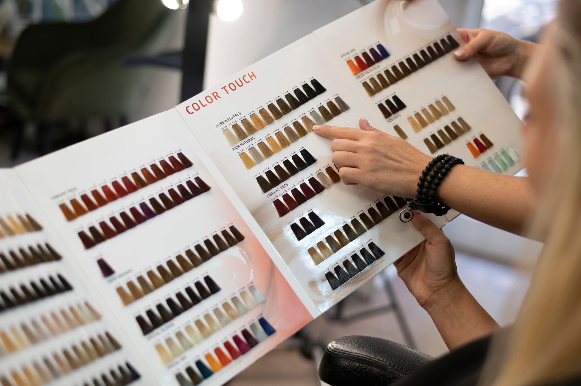 A woman is looking at a hair color chart in a salon.