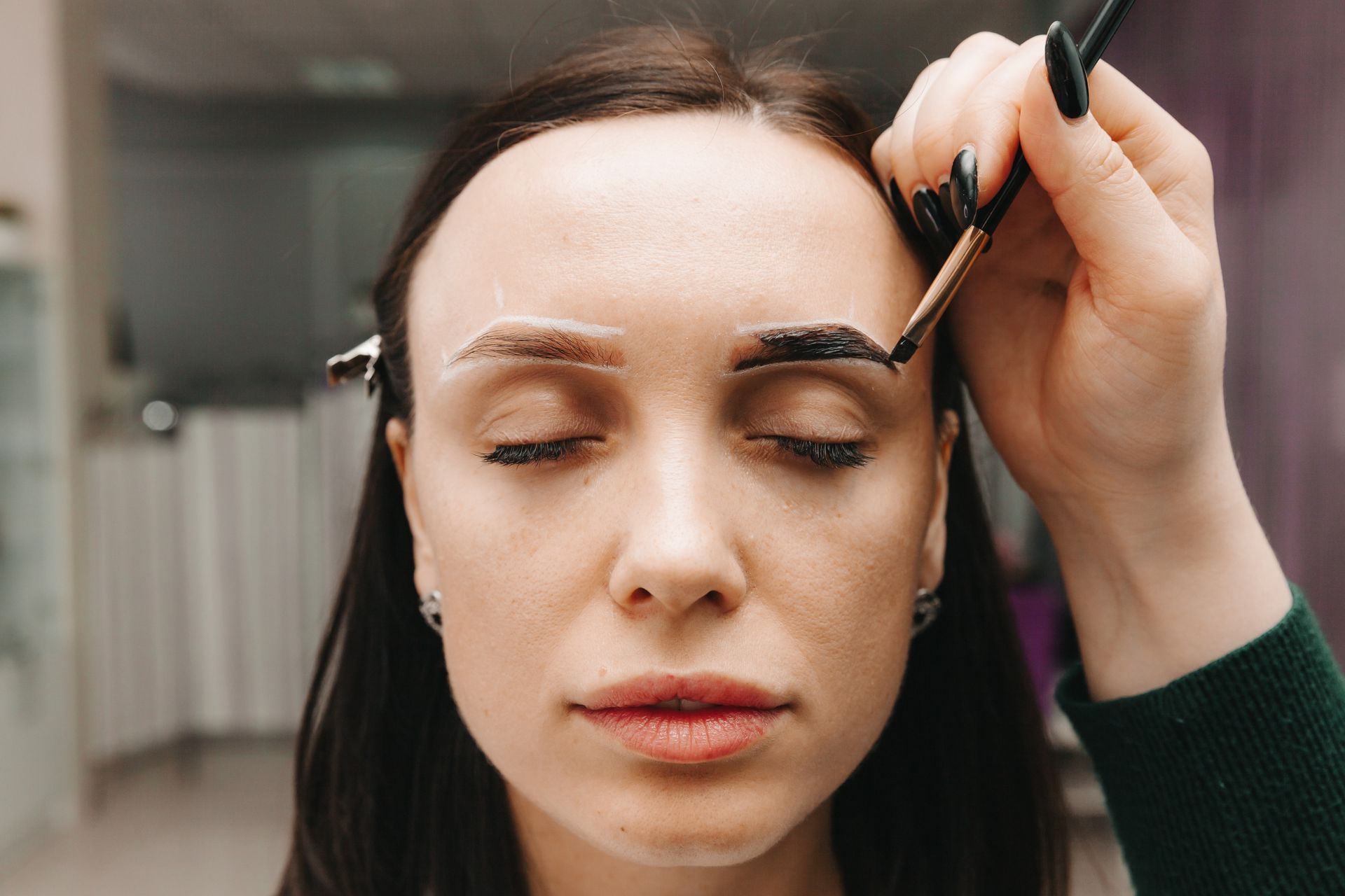 A woman is getting her eyebrows painted in a salon.