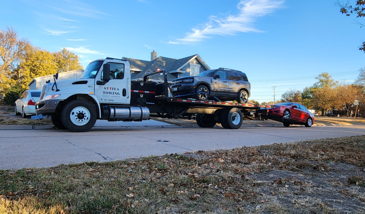 A tow truck is carrying a bunch of cars on a trailer.