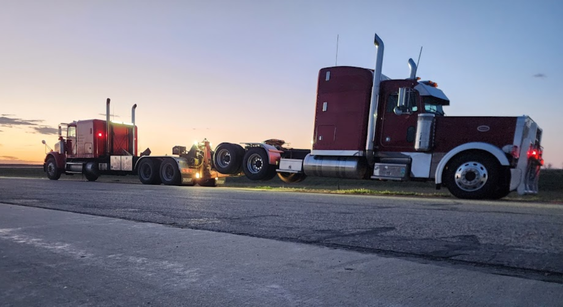Two semi trucks are parked on the side of the road.