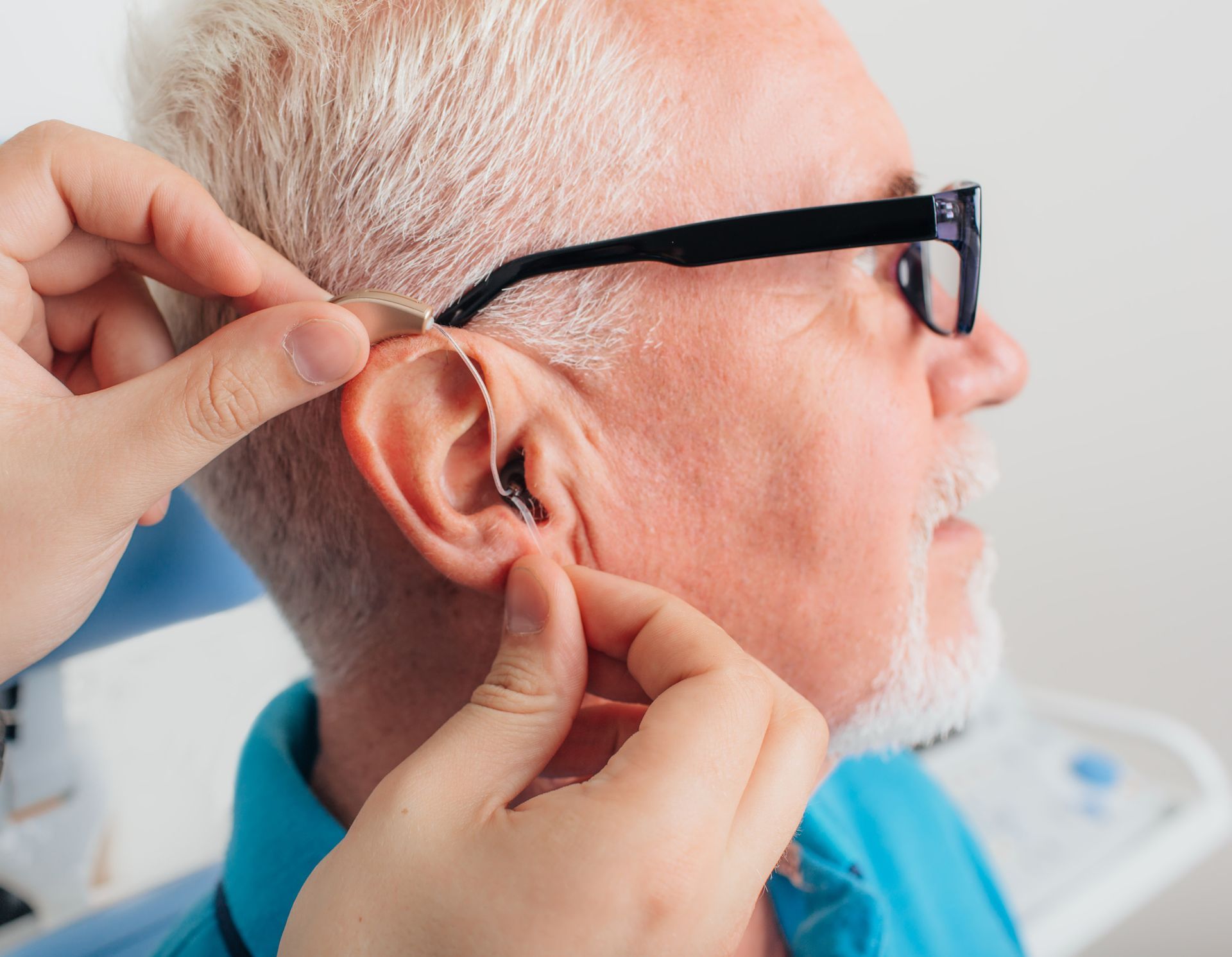 A man is getting a hearing aid put in his ear.