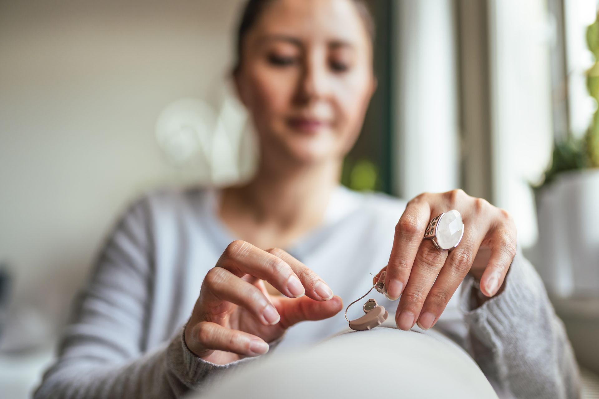 A woman is sitting on a couch painting her nails.