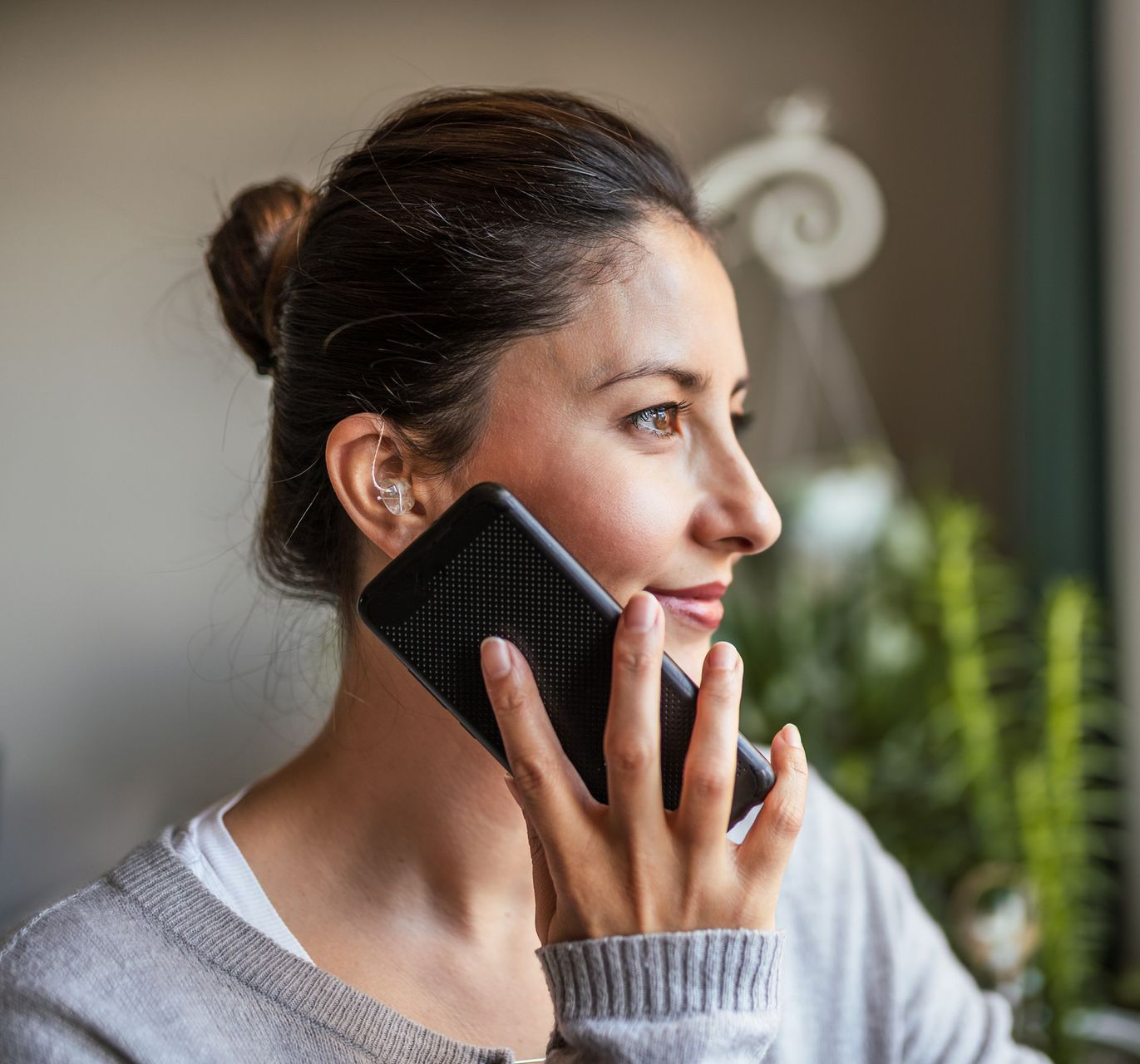 A woman is talking on a cell phone in front of a window.