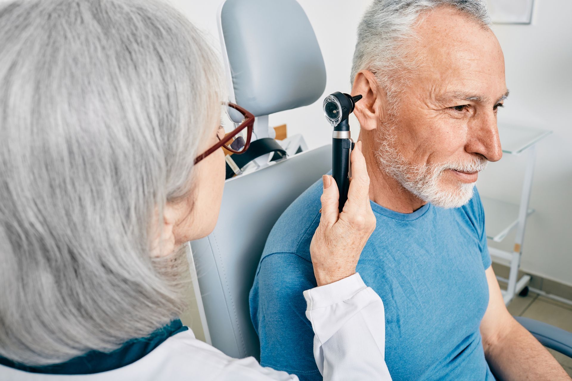 A doctor is examining a man 's ear with an otoscope.