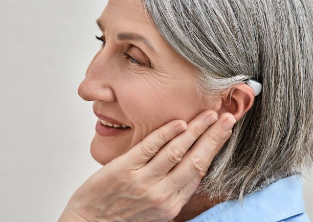 A woman with gray hair is wearing a hearing aid.