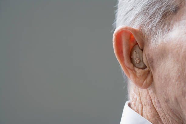 A close up of an elderly man 's ear with a hearing aid.