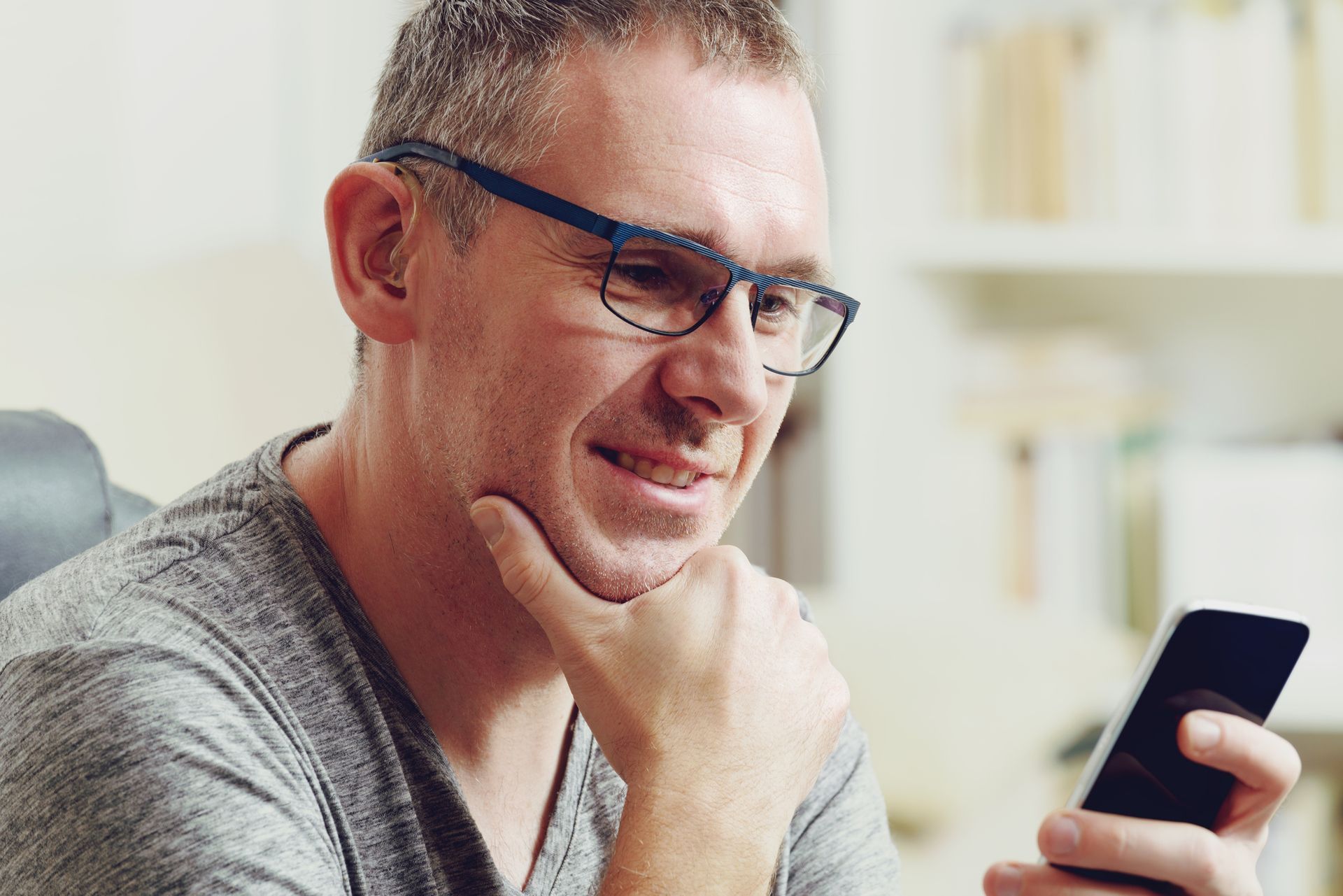 A man wearing glasses is looking at his cell phone.