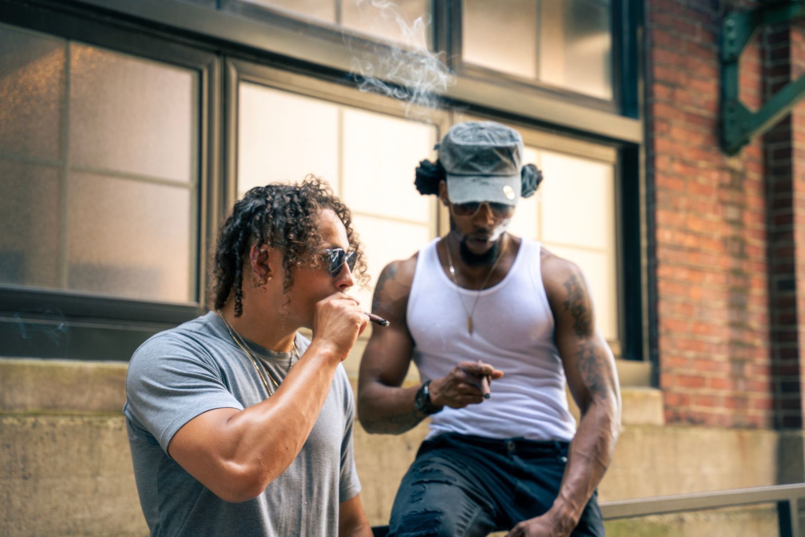 Two men smoking cigars in an alley