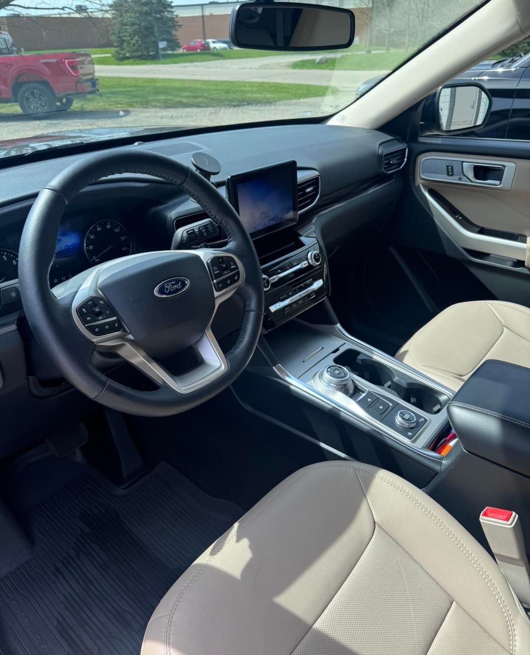 Interior view of a Ford Explorer. Beige seats, black dashboard, steering wheel, and center console with a touchscreen display.