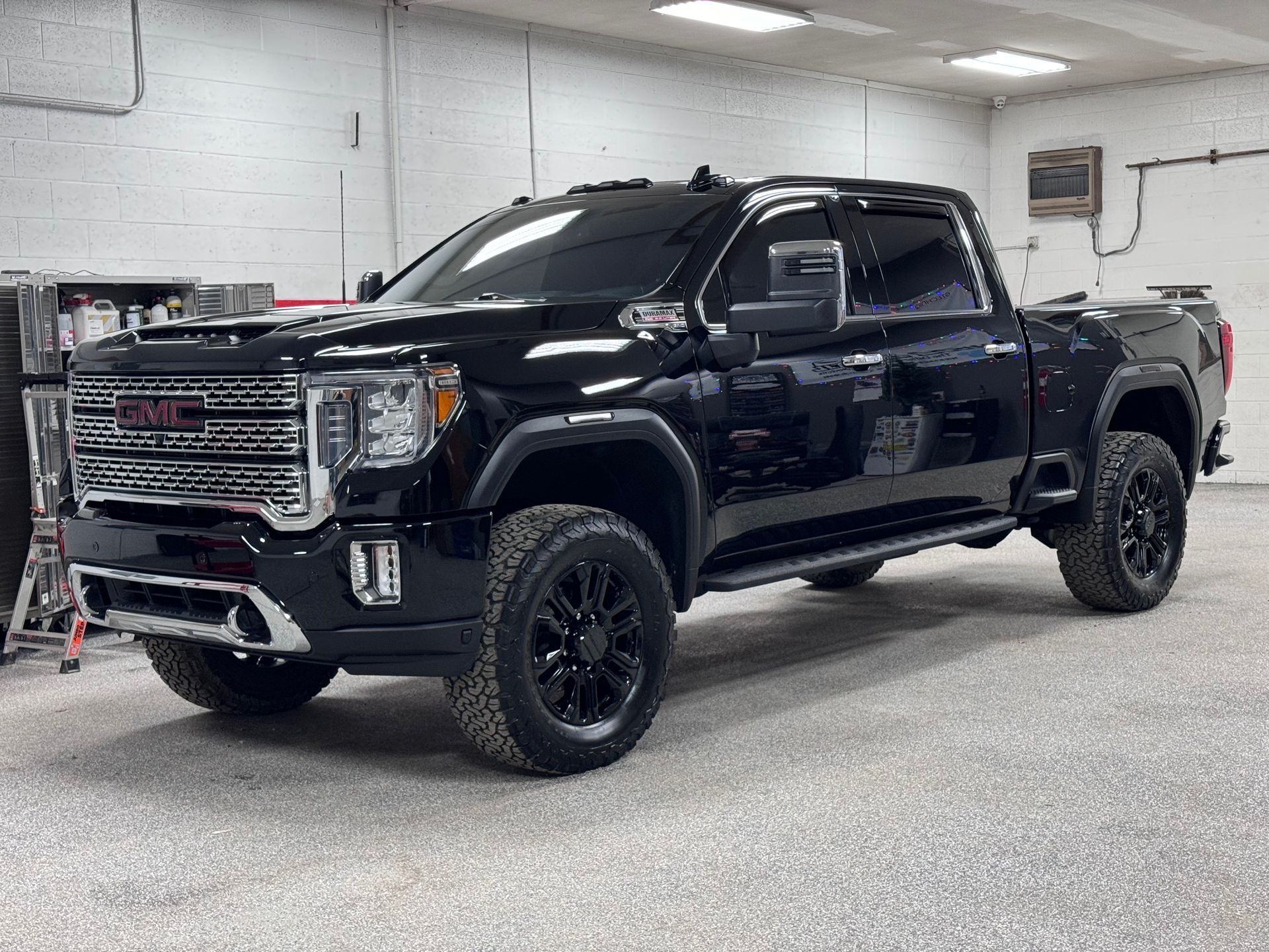 Black GMC Sierra heavy-duty truck parked in a garage with black rims and tinted windows.