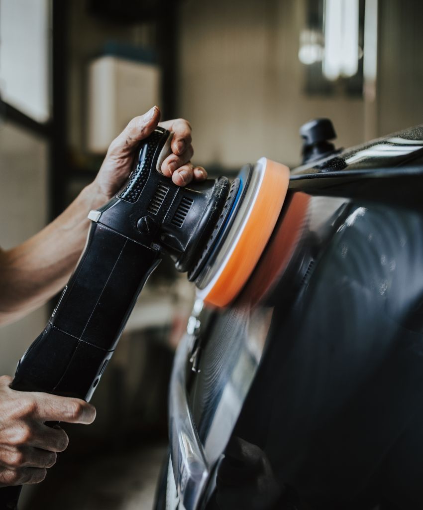 A person is polishing a car with a machine.