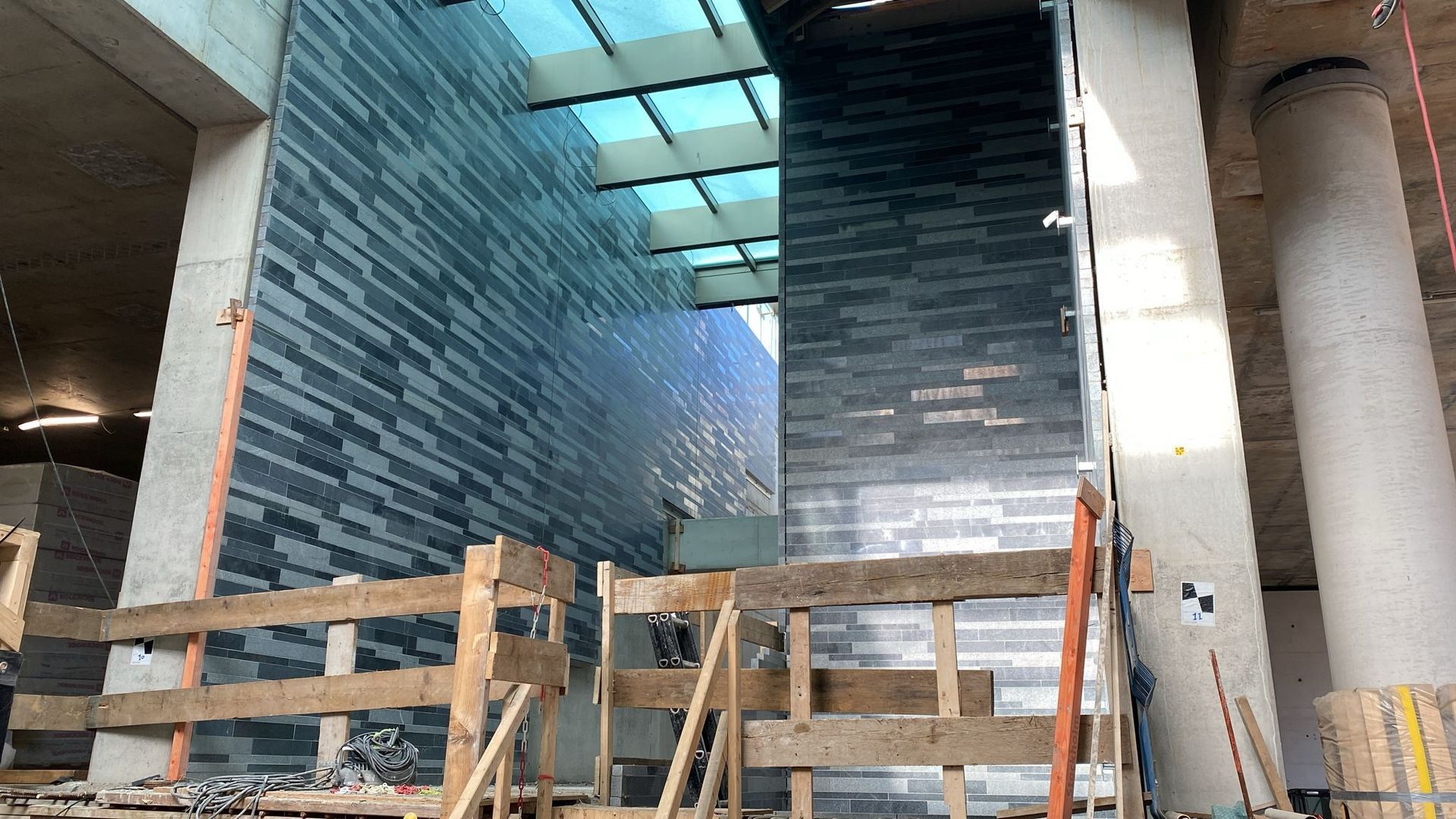 Een man installeert granieten tegels op de zijkant van een gebouw.