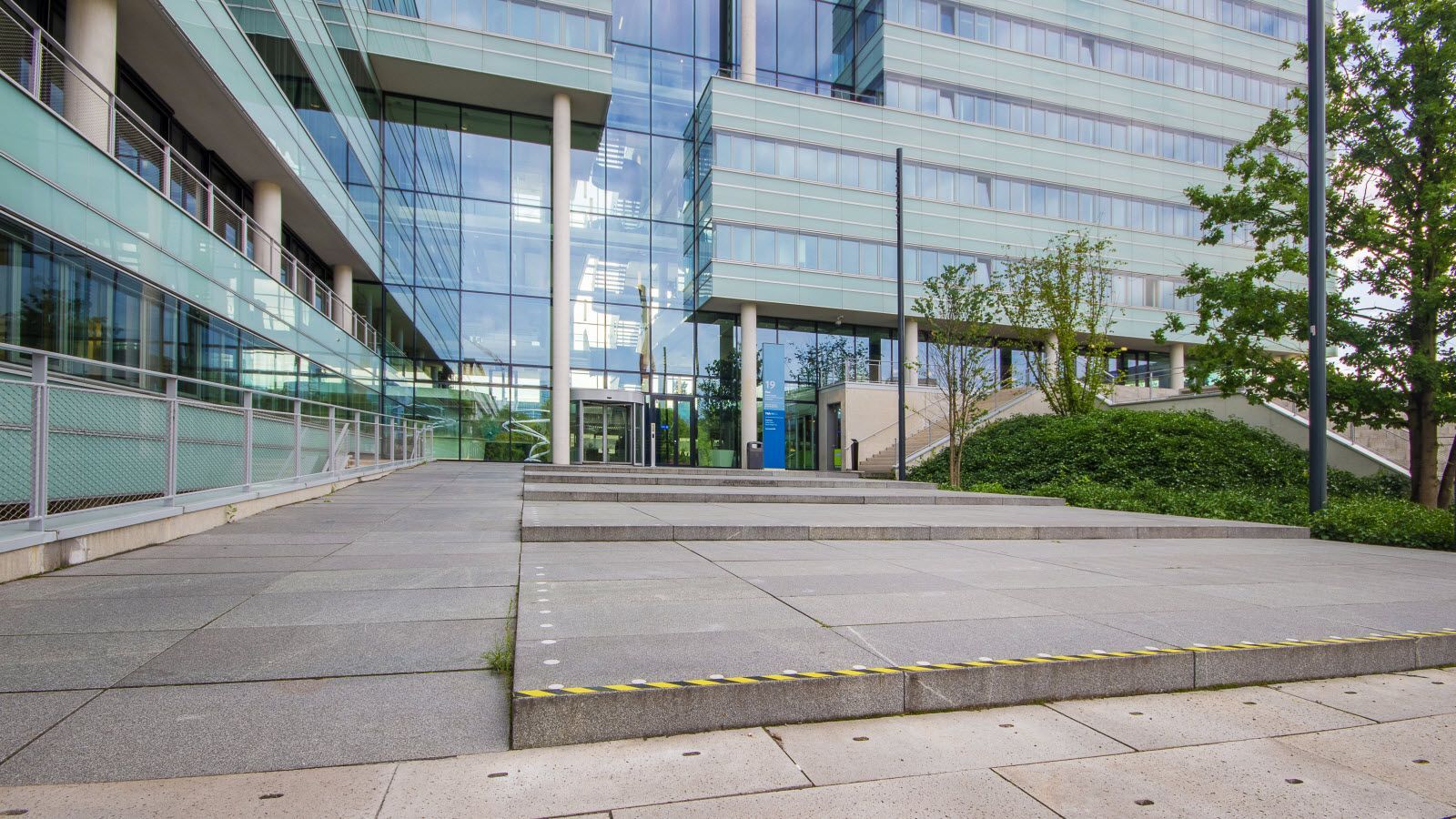 Een groot glazen gebouw met een trap ernaartoe.