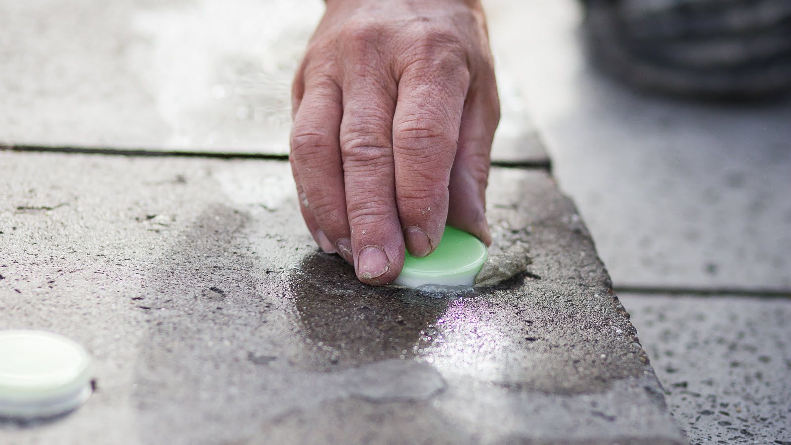 Iemand maakt een tegelvloer schoon met een spons.