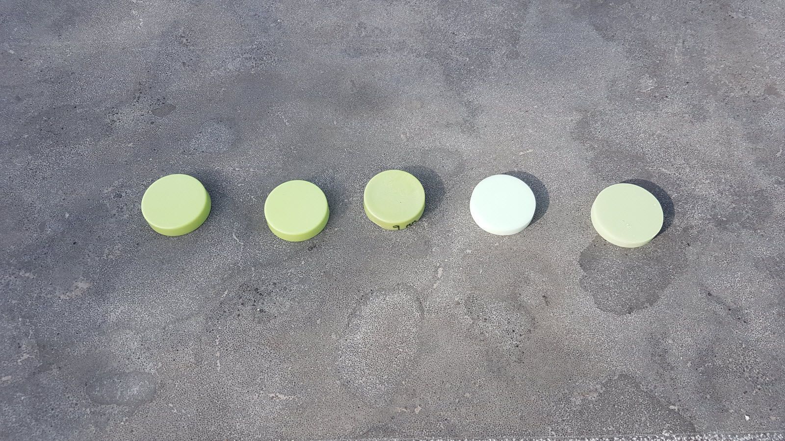 Een rij groene en witte cirkels op een grijs oppervlak.