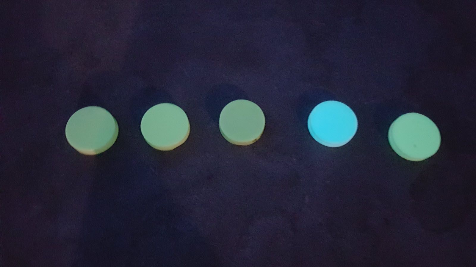 Een rij lichtgevende cirkels op een donker oppervlak.