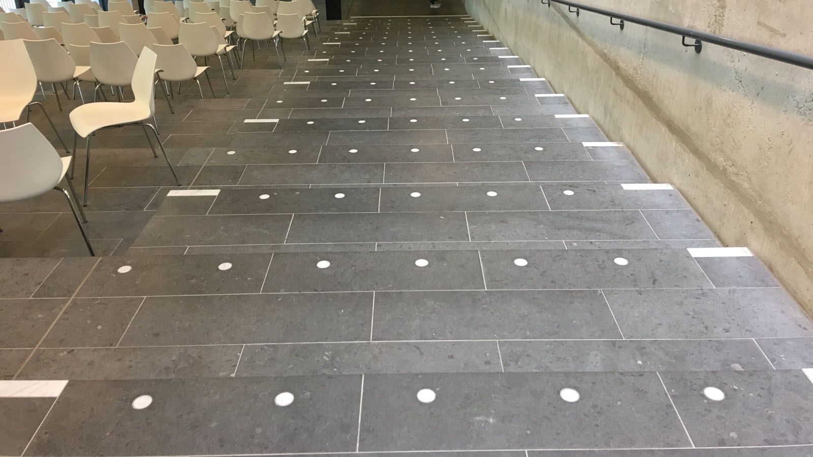 Een rij witte stoelen staat op een betegelde vloer.