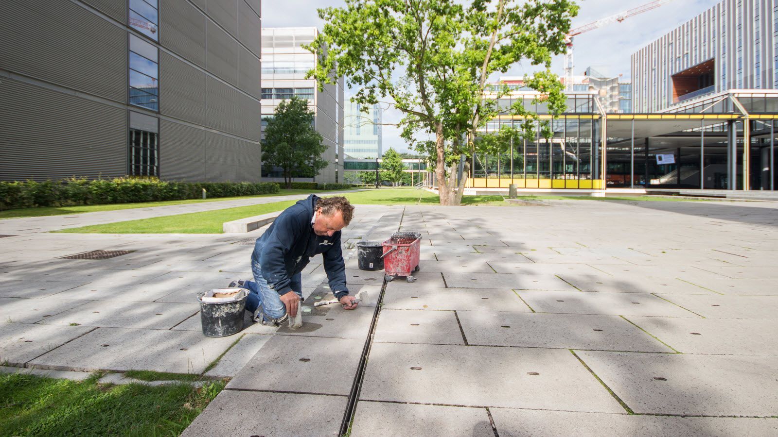Een man knielt op de stoep voor een gebouw.