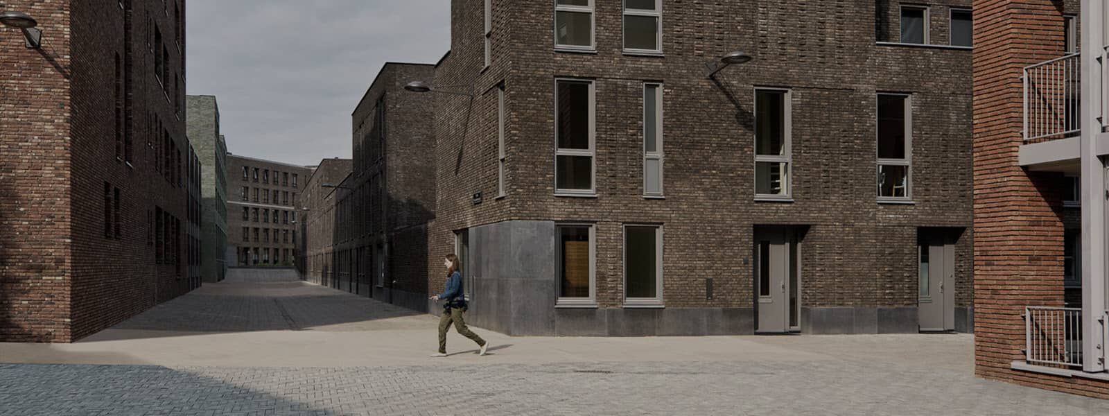 Een man loopt over straat tussen twee bakstenen gebouwen.