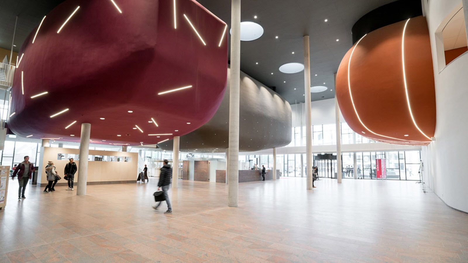 Een groep mensen loopt door een grote lobby van een gebouw.