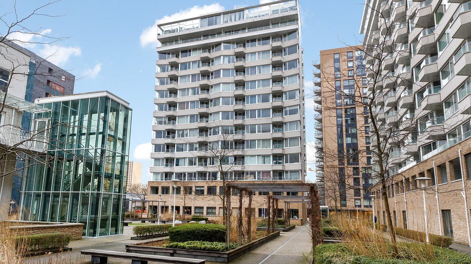 Een groot gebouw met veel ramen wordt omringd door kleinere gebouwen.