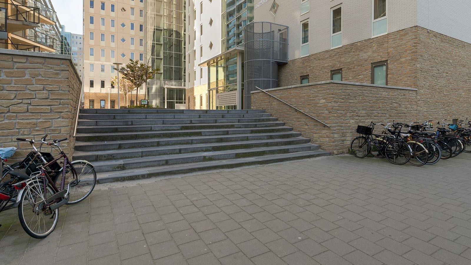 Een rij fietsen staat geparkeerd op de stoep voor een gebouw.