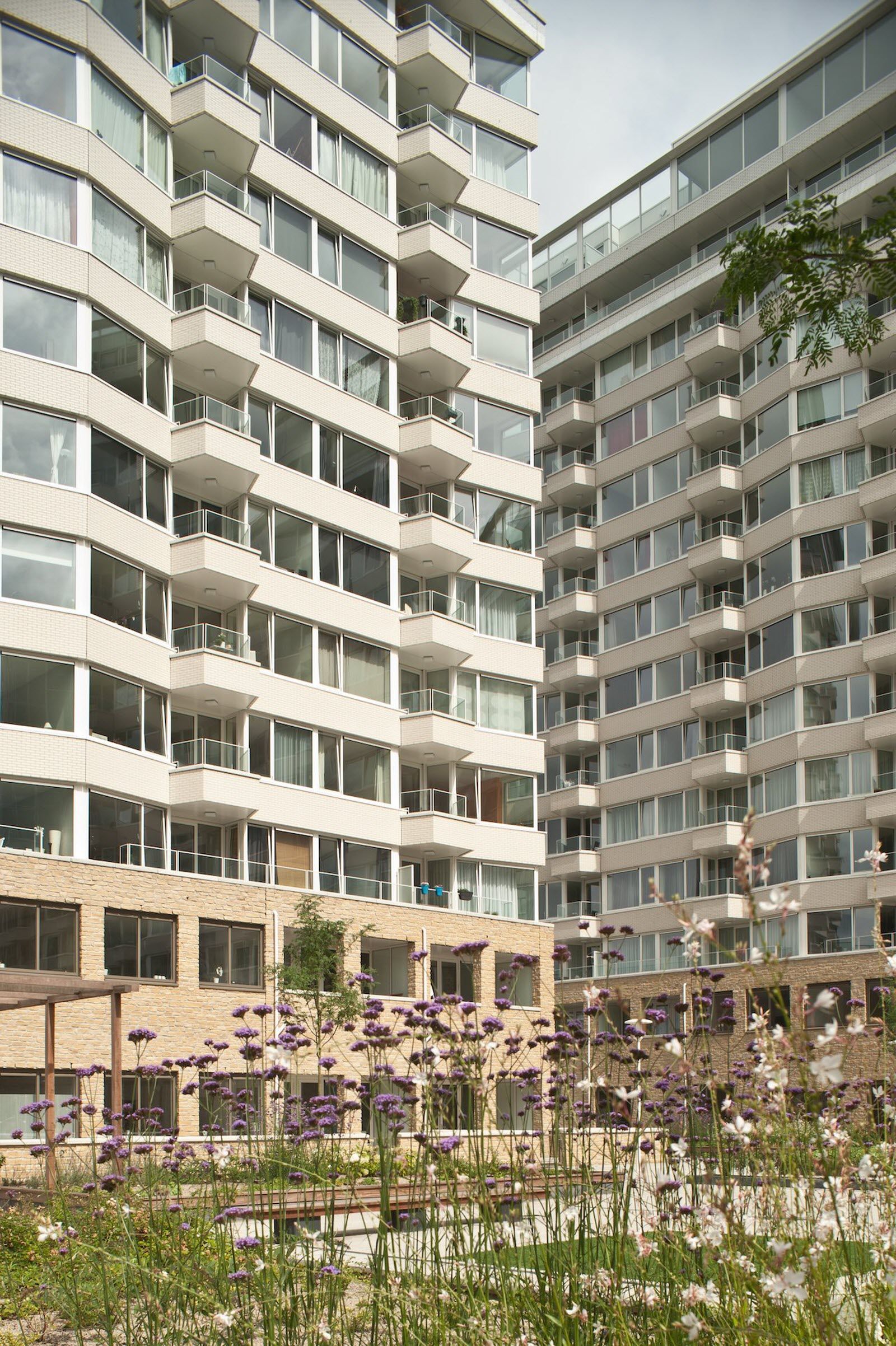 Een groot gebouw met veel ramen en bloemen ervoor.