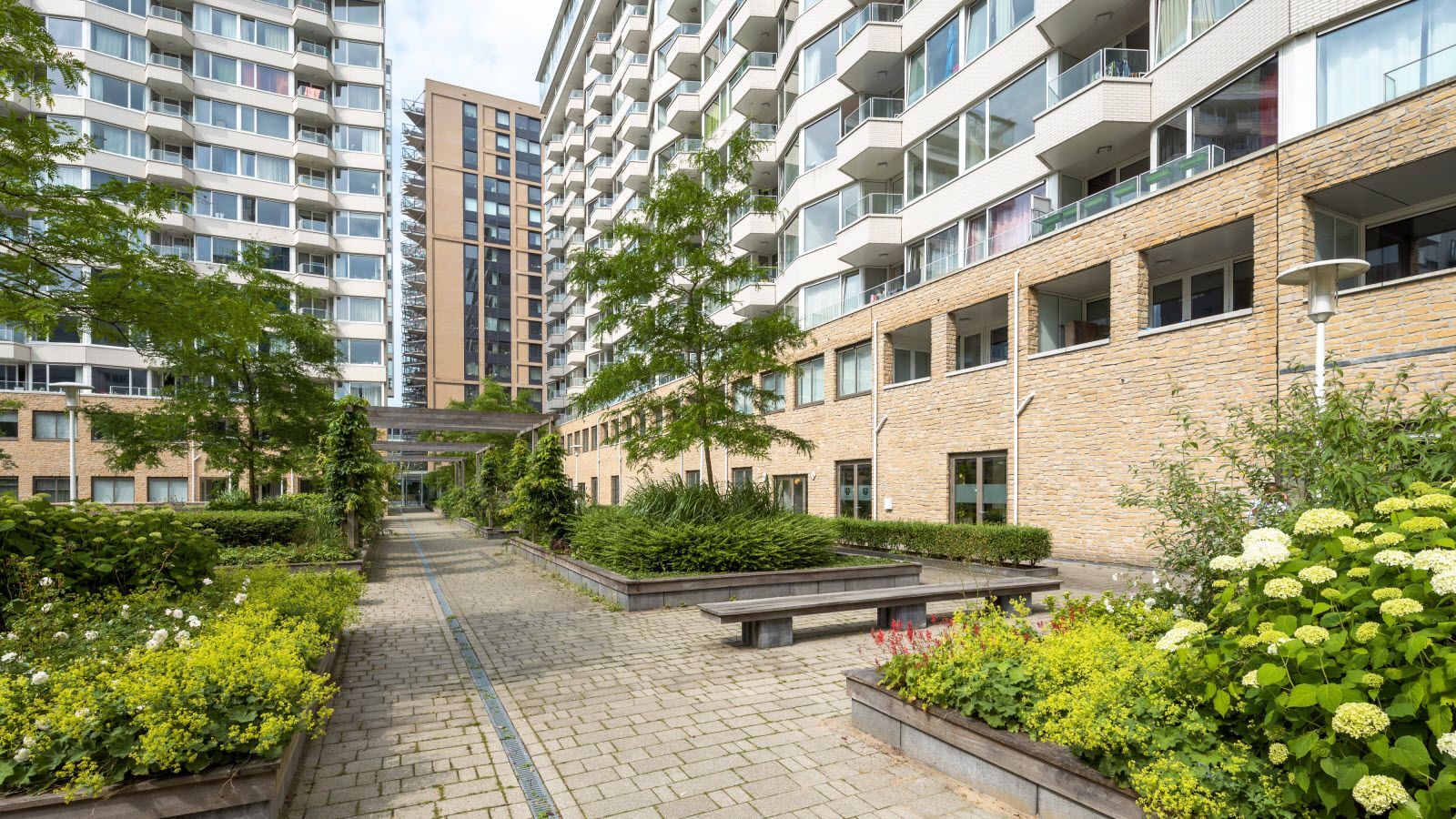 Een groot appartementengebouw met een tuin ervoor.