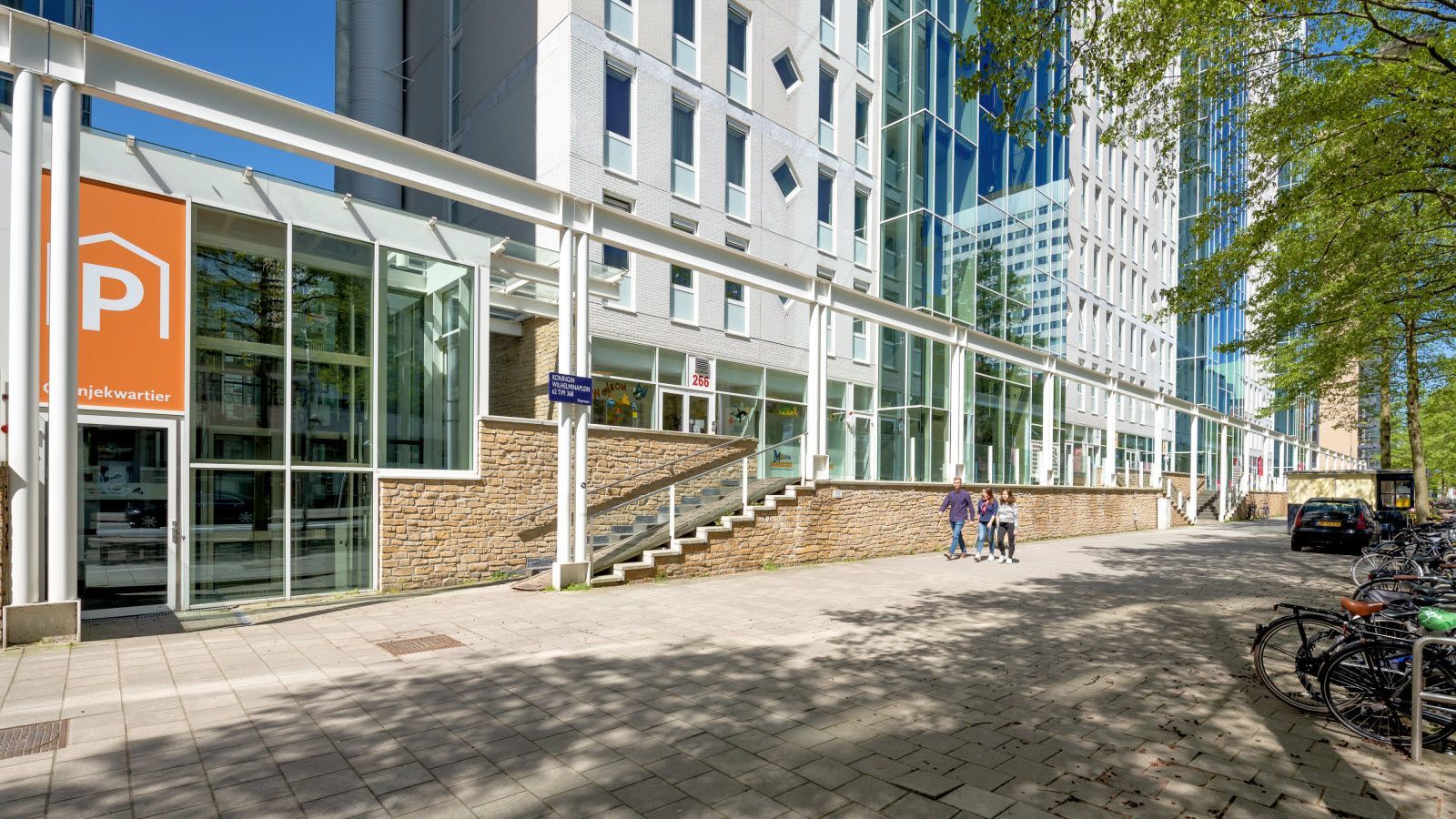 Een groot gebouw met veel ramen en ervoor geparkeerde fietsen.