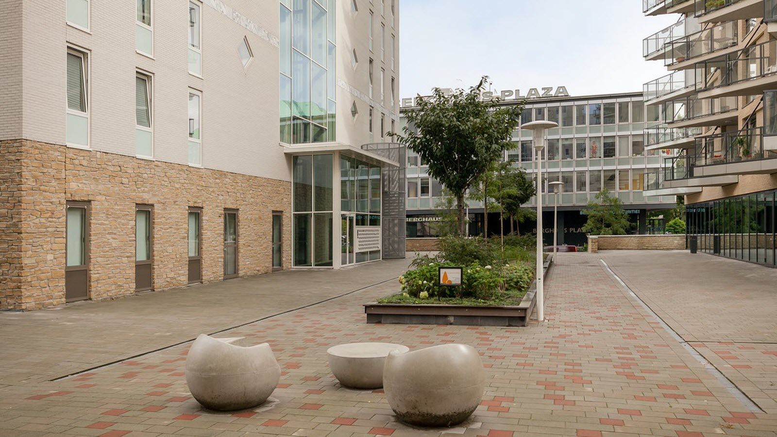 Een groep betonnen ballen ligt op een stoep van bakstenen voor een gebouw.
