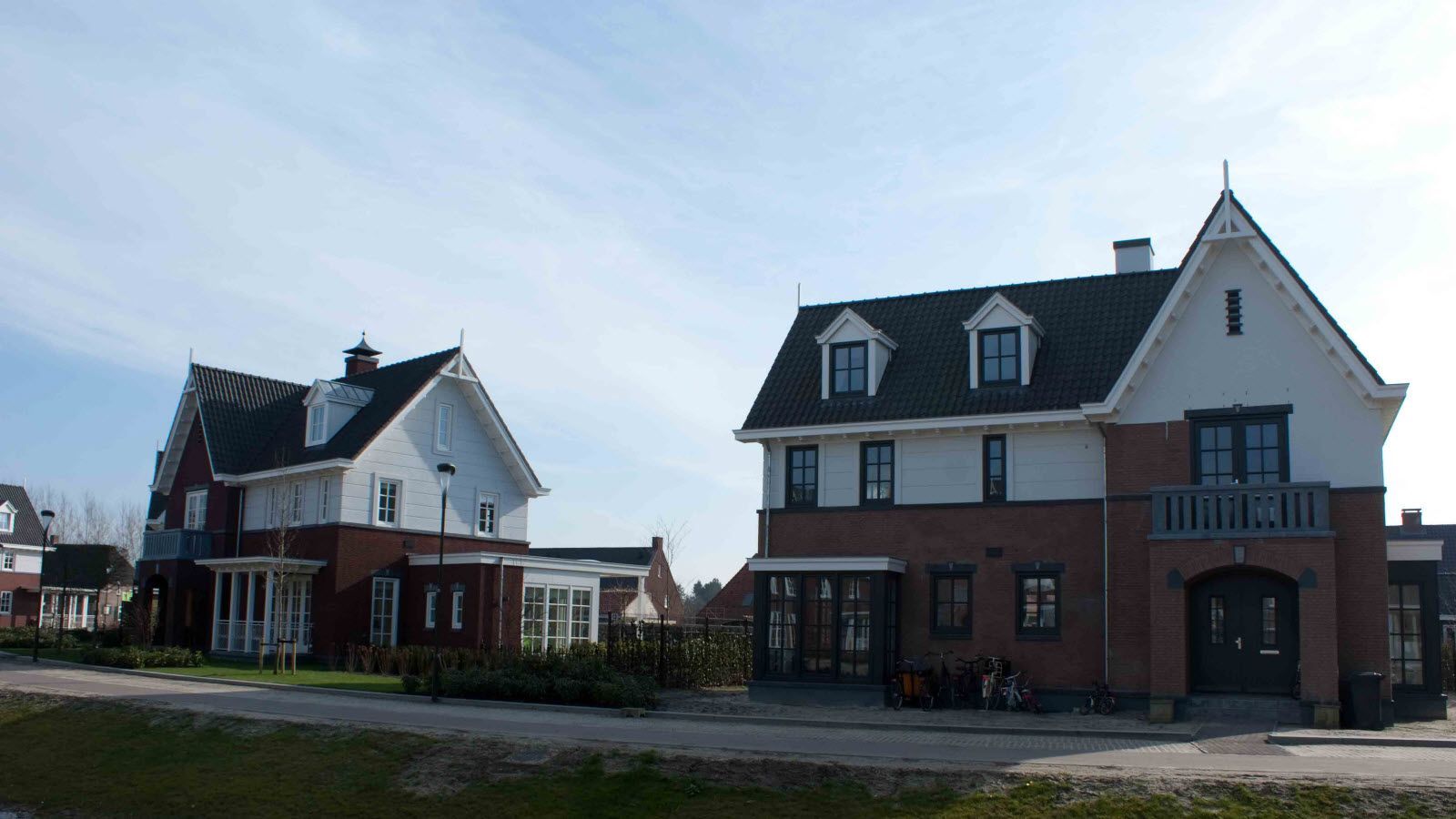 Twee huizen met zwarte daken staan naast elkaar