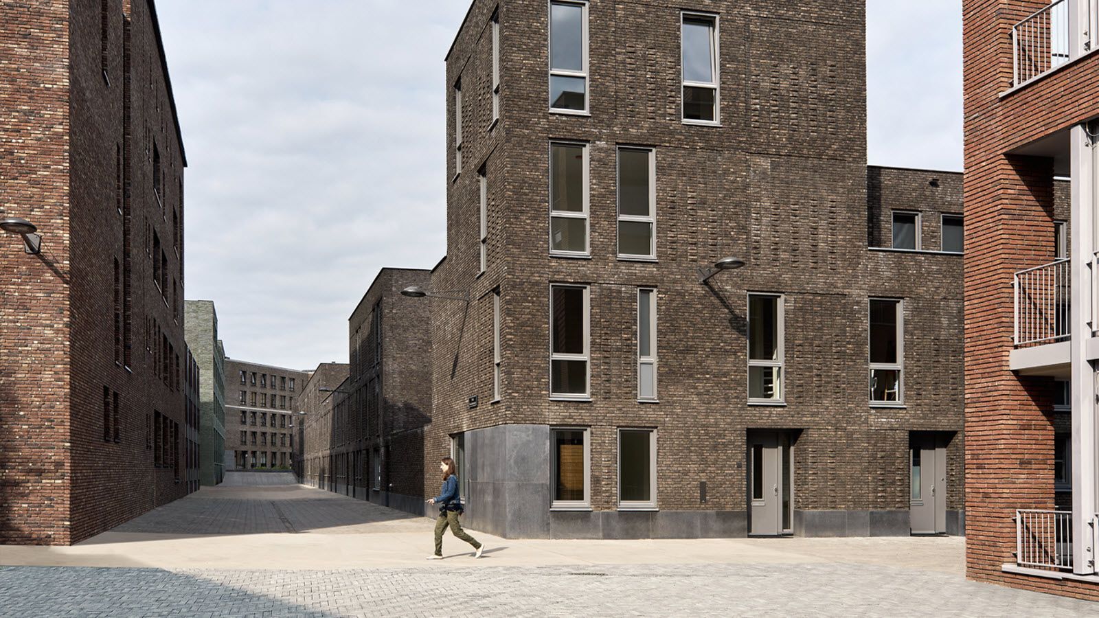 Een man loopt over straat tussen twee bakstenen gebouwen.