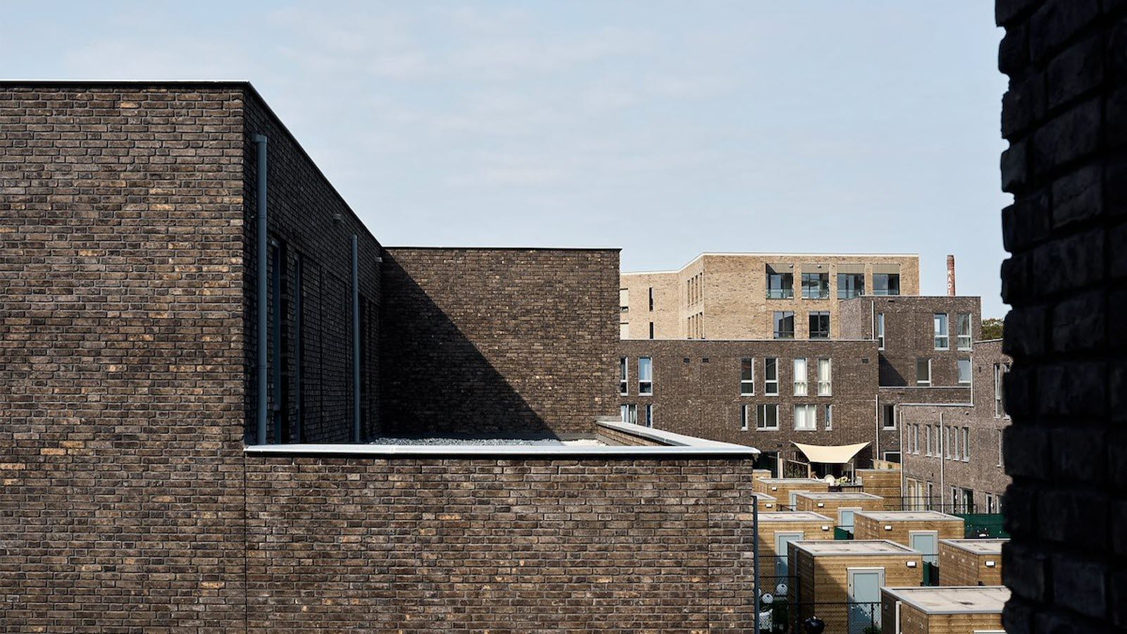 Een bakstenen gebouw met veel ramen wordt omringd door andere bakstenen gebouwen.
