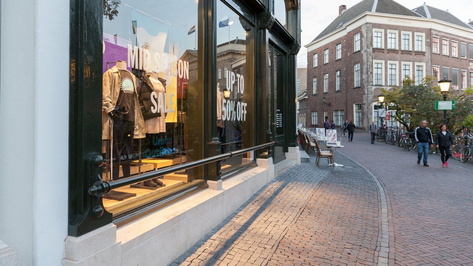 Een winkelpui met een weerspiegeling van een gebouw in de etalage.