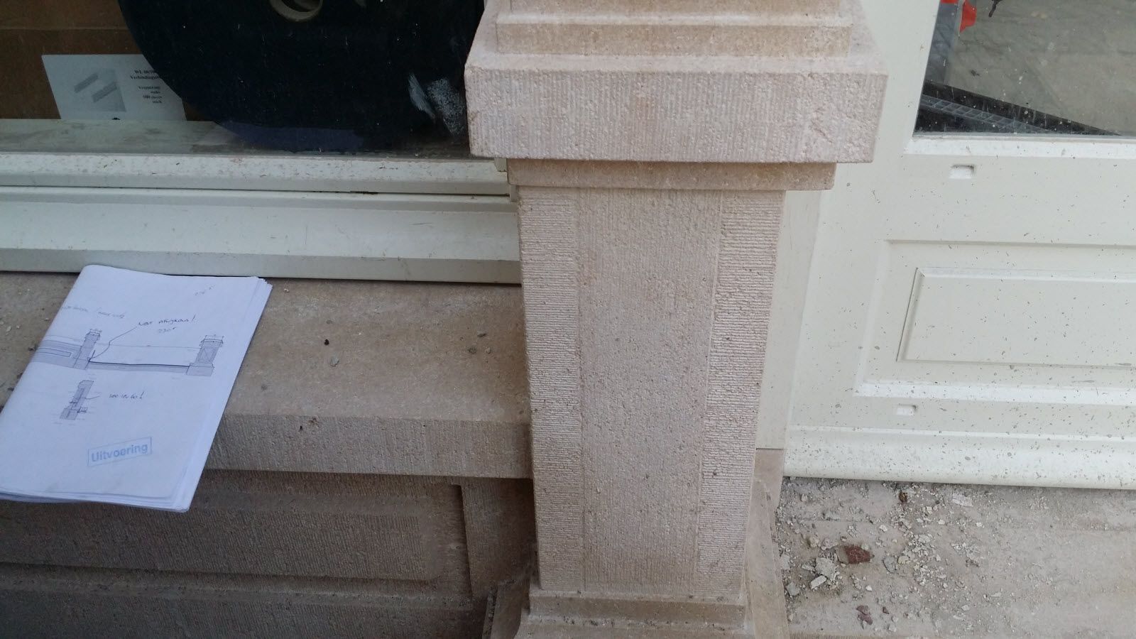 Er staat een pilaar naast een deur met een stuk papier erop.