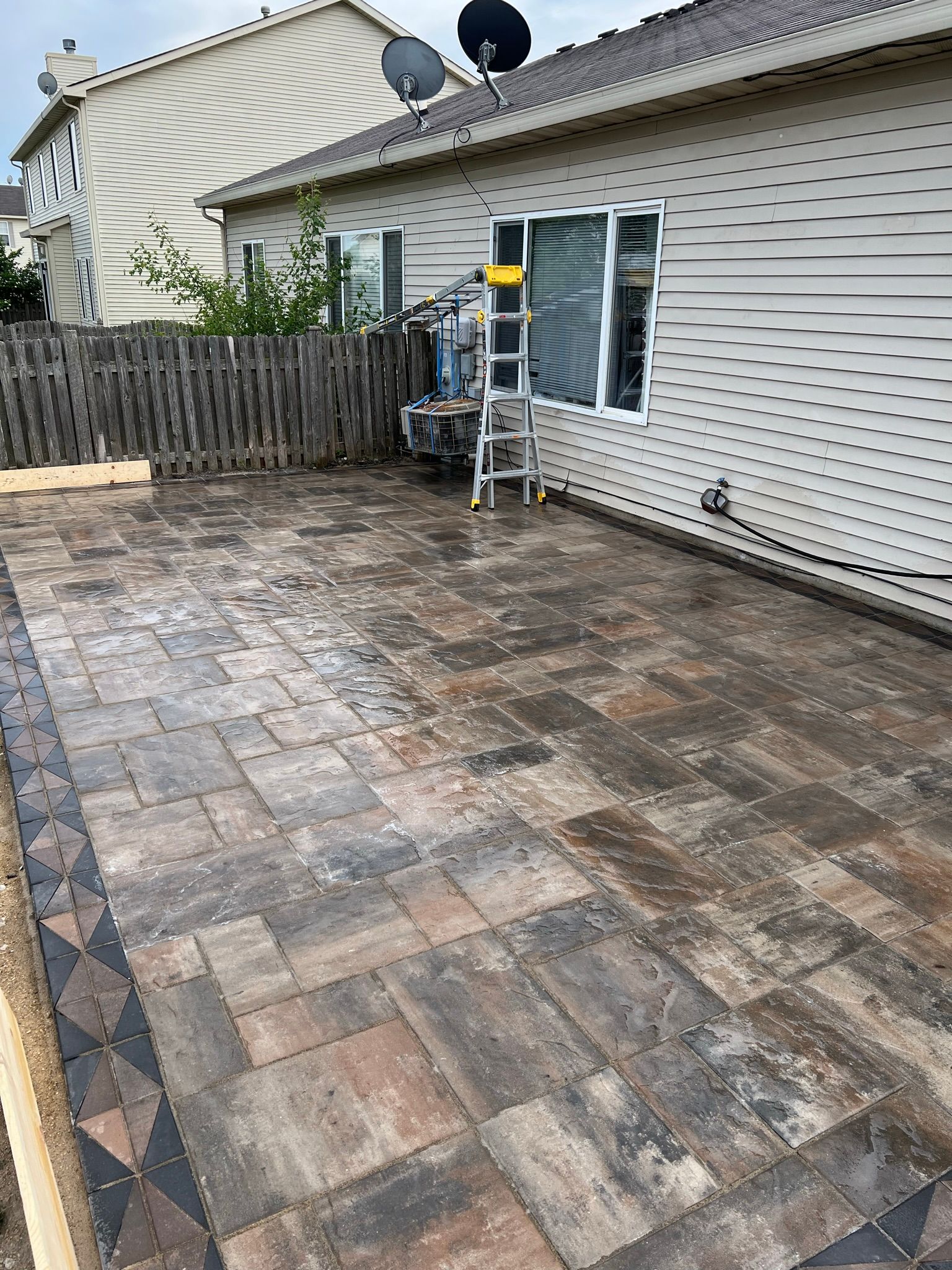 A patio with a ladder in front of a house.