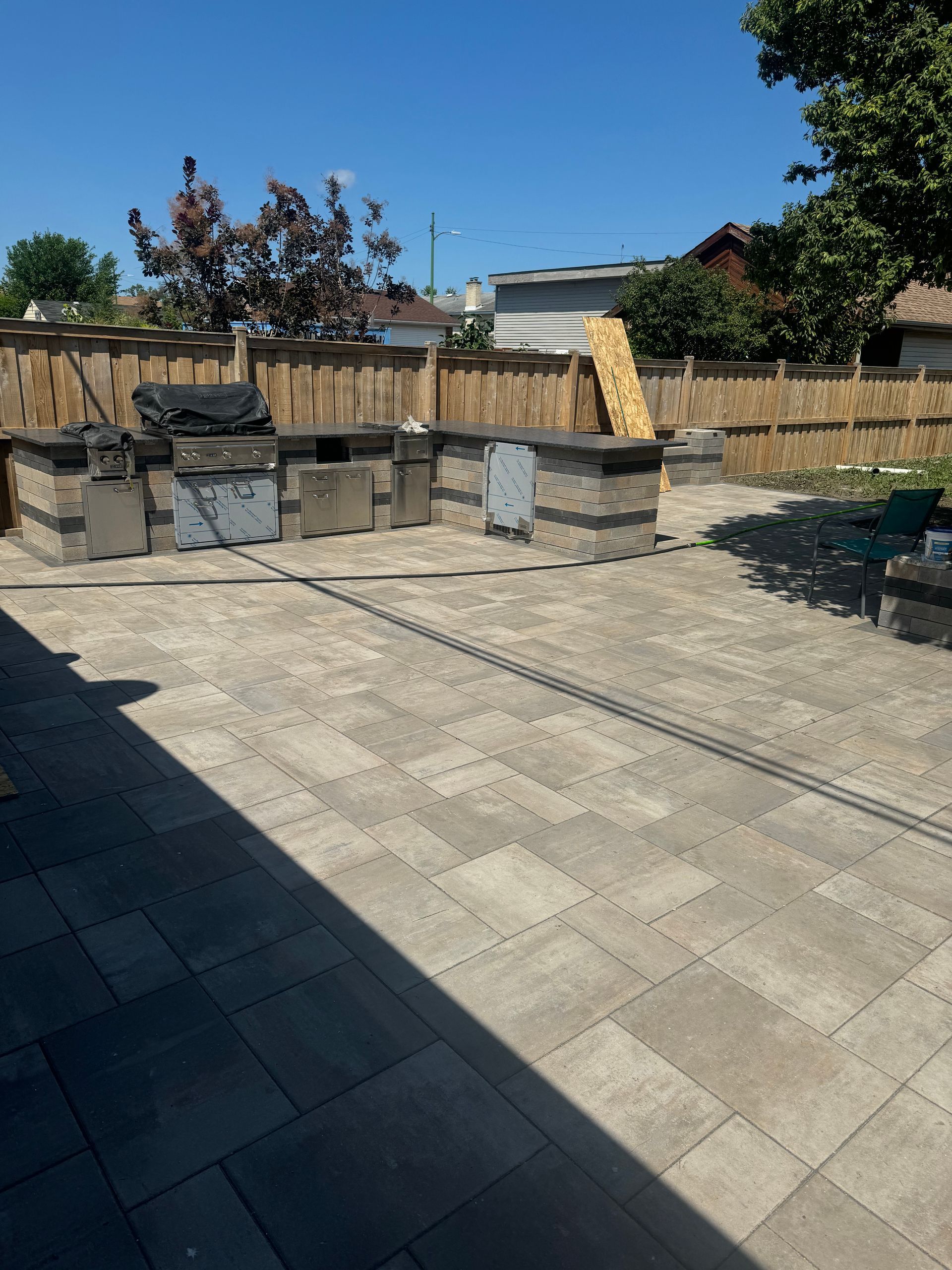 A patio with a grill and a fence in the background
