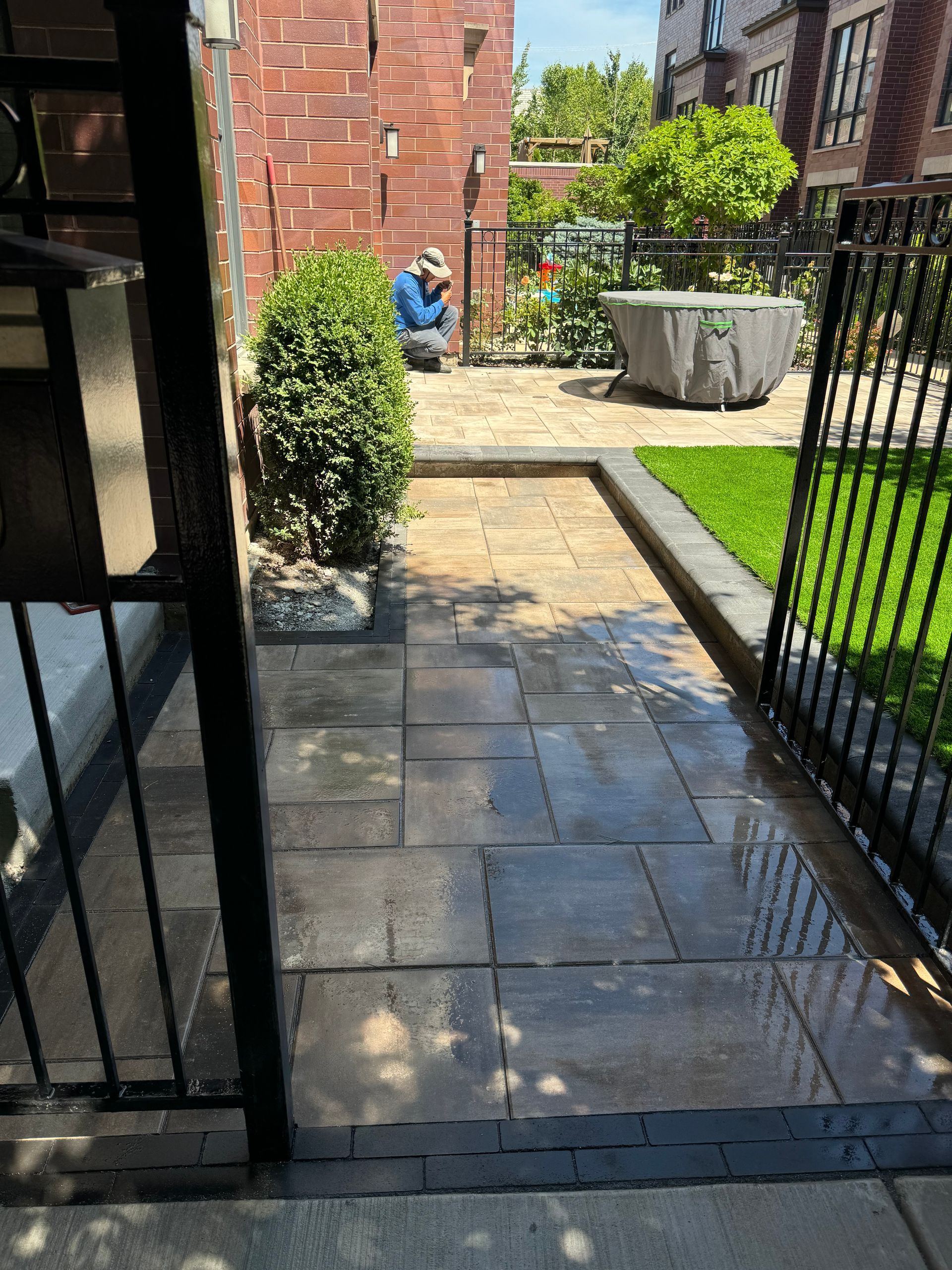 A man is sitting on a patio next to a fence.