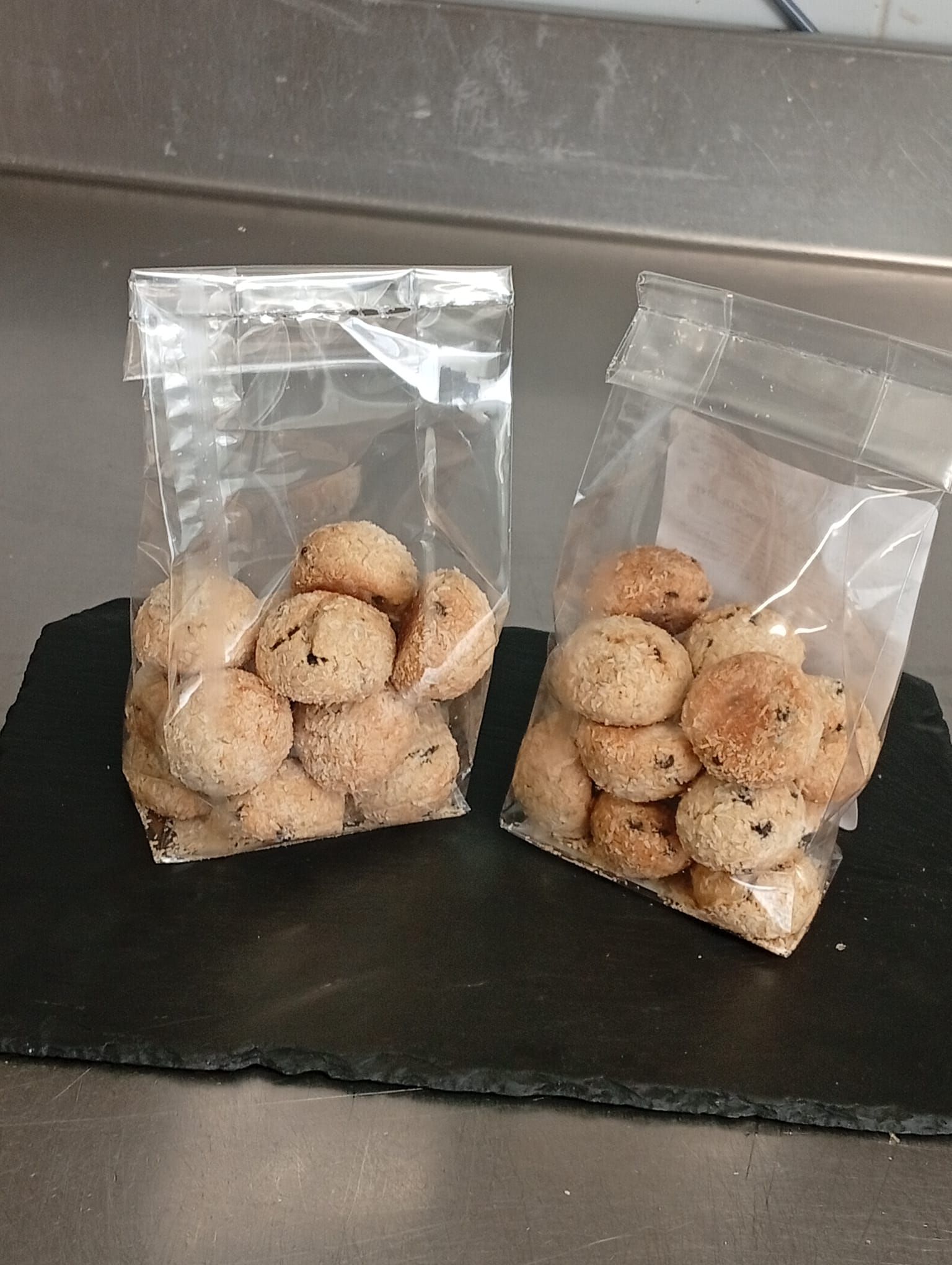 Due sacchetti di plastica trasparente pieni di piccoli biscotti rotondi color marrone chiaro