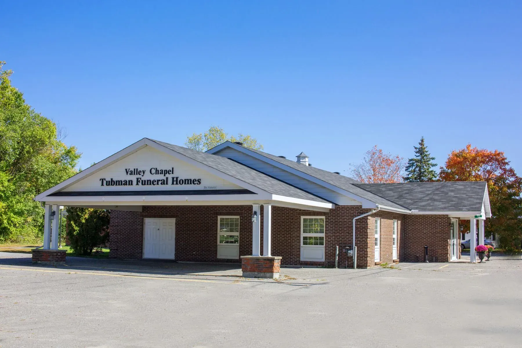 A small brick building with a porch and a blue sky in the background.