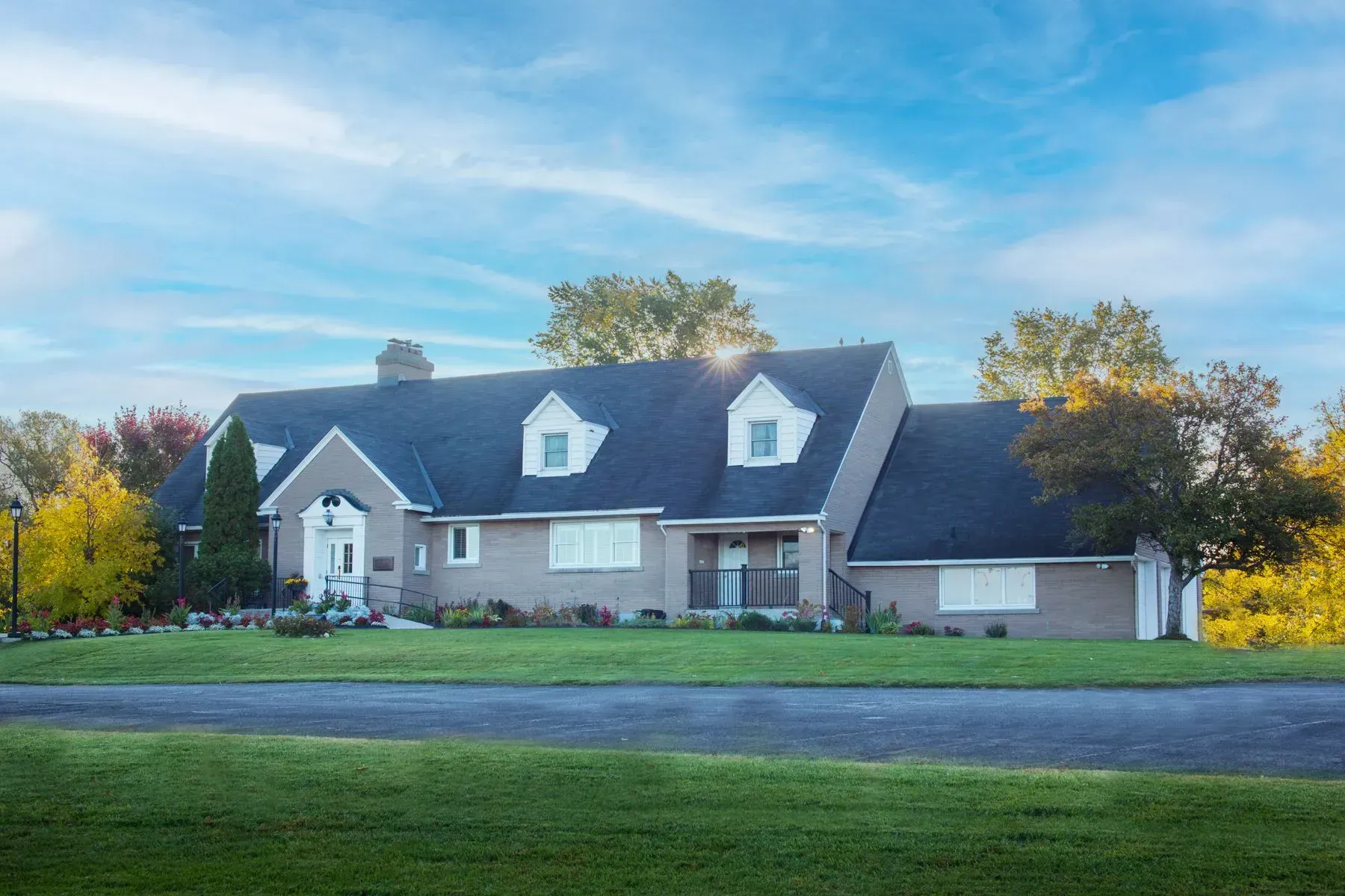 A large house with a black roof is sitting on top of a lush green field.