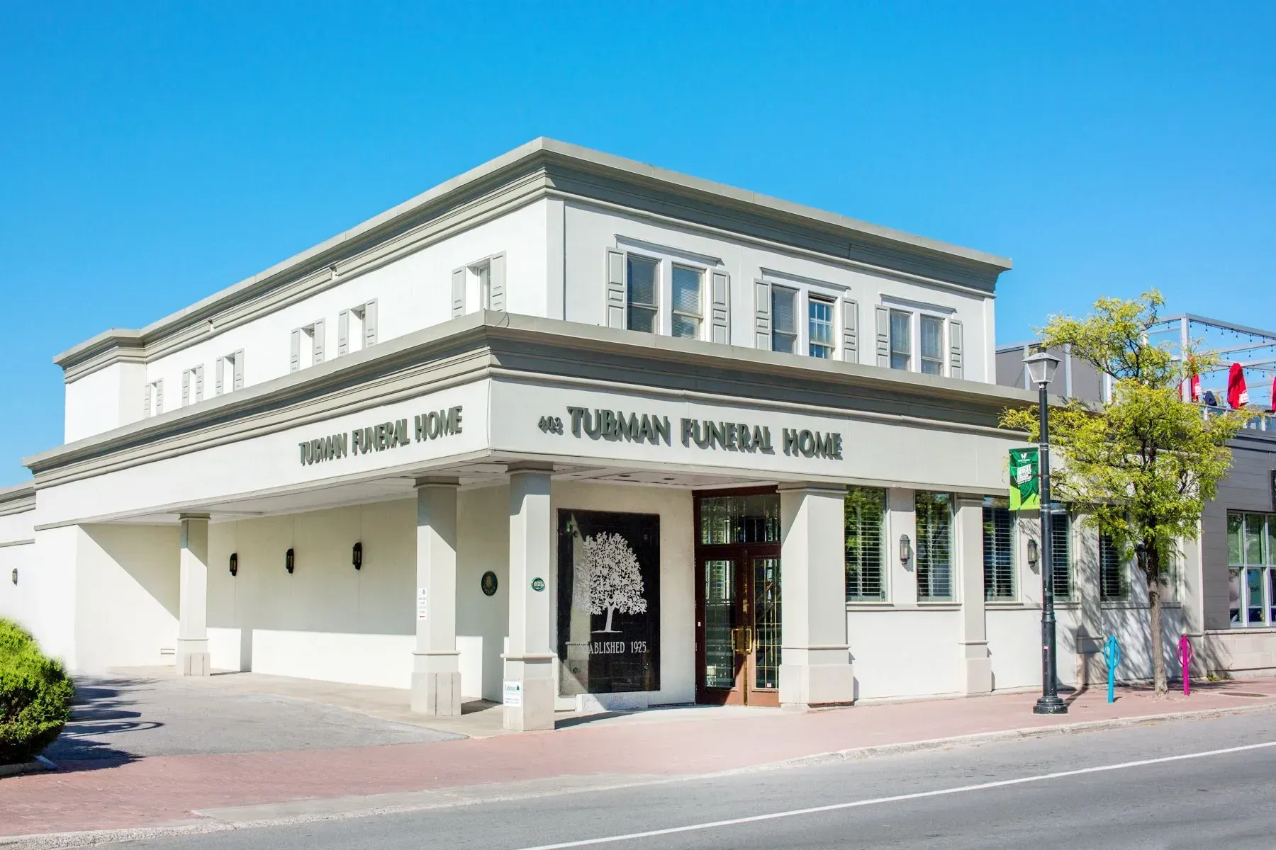 A large white building with a tree on the front of it is a funeral home.