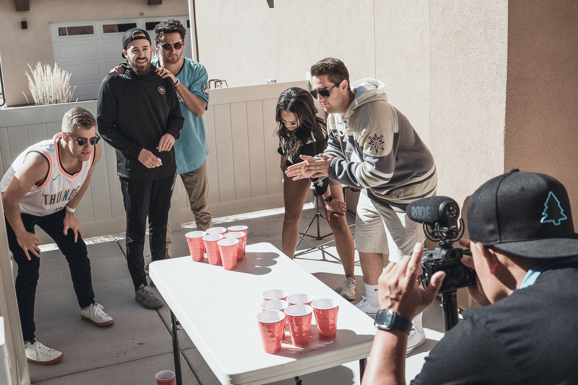 A man is taking a picture of a group of people playing beer pong.