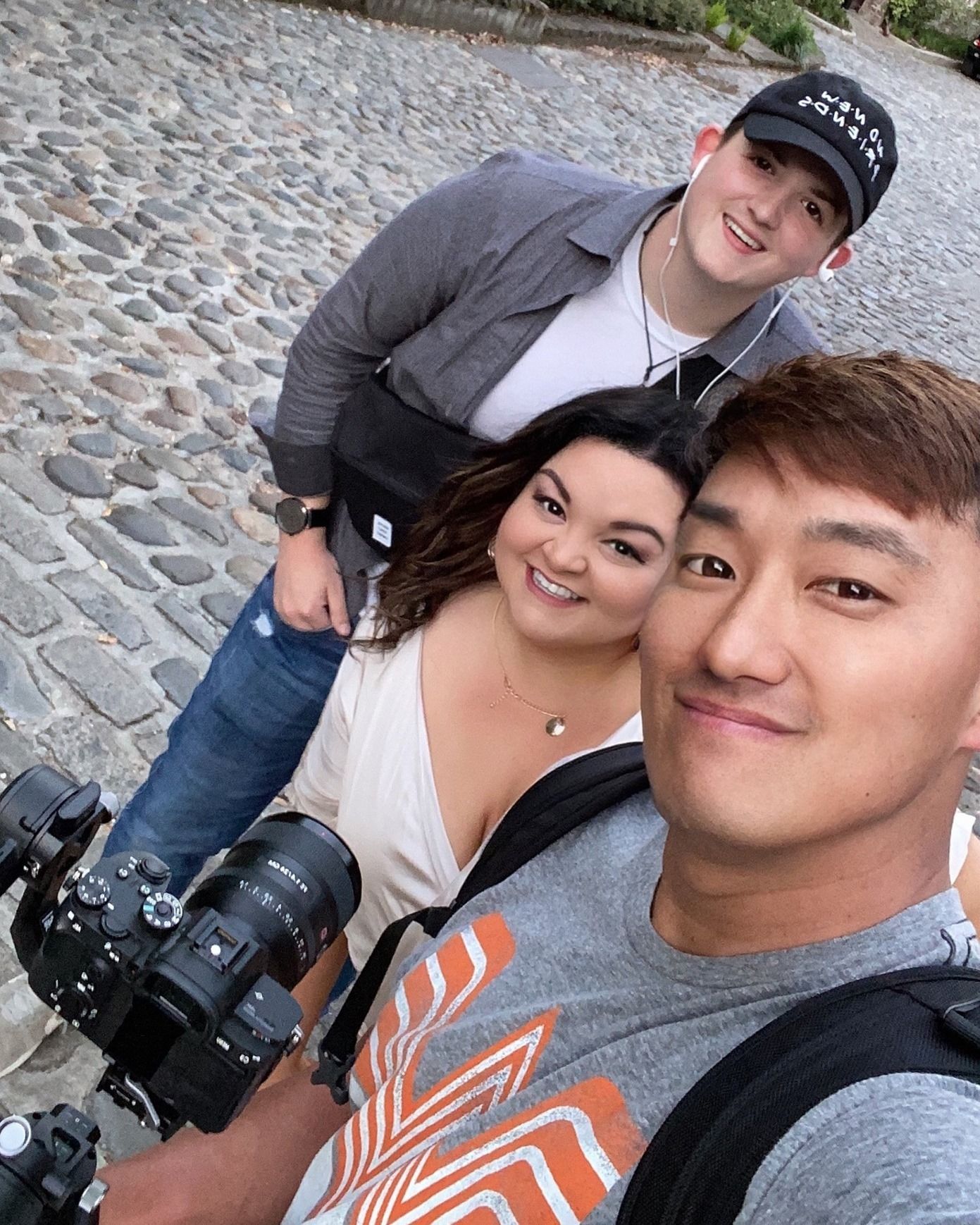 A man is taking a selfie with two other people while holding a camera.