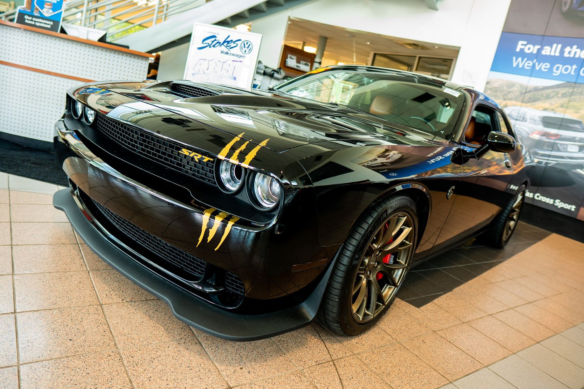 A black dodge challenger is parked in a showroom.