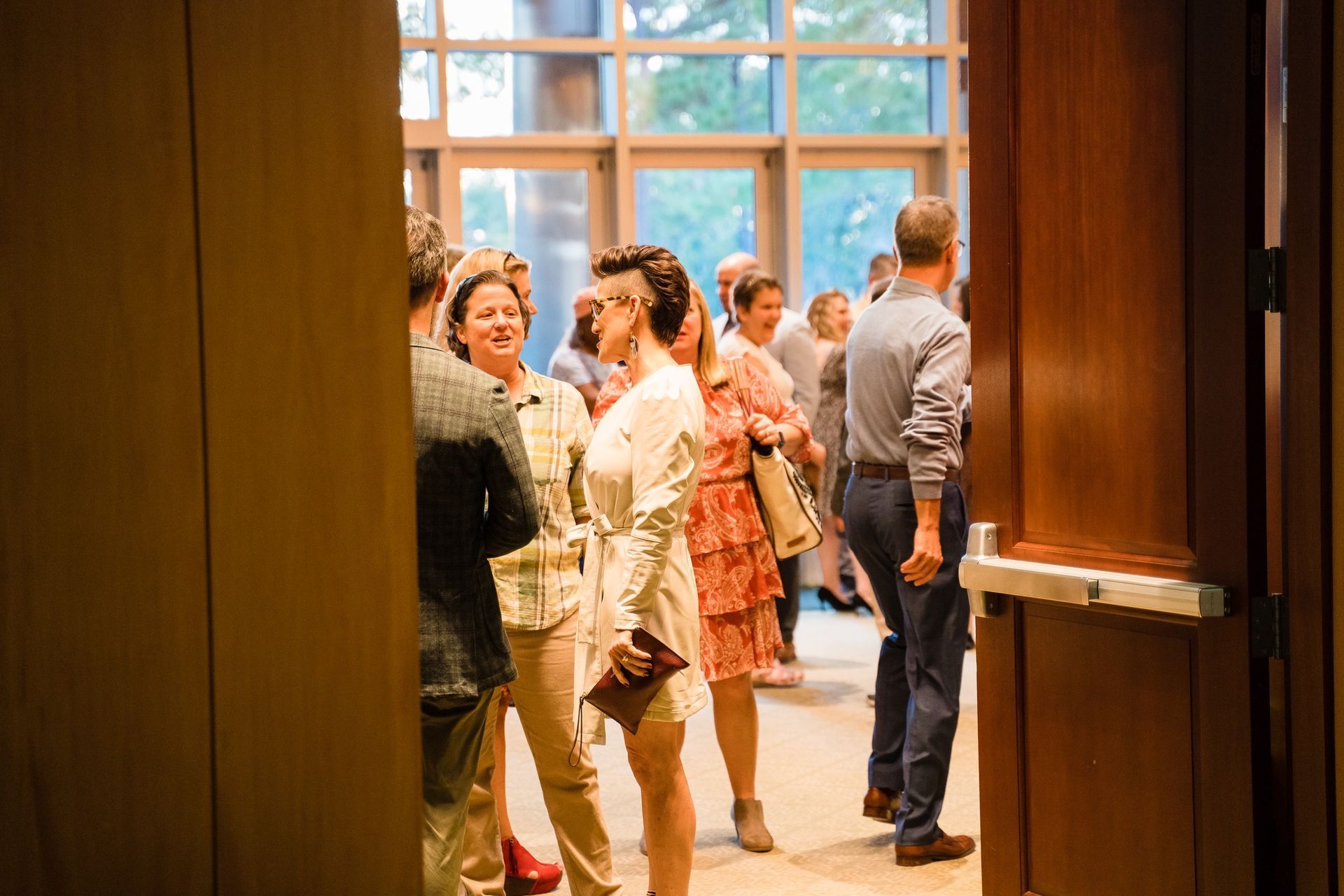 A group of people are standing in a room talking to each other.