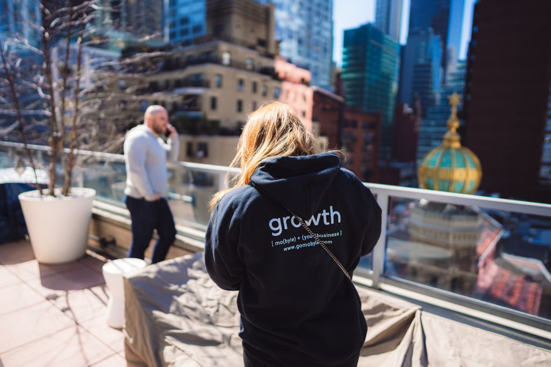 A man and a woman are standing on a balcony overlooking a city.
