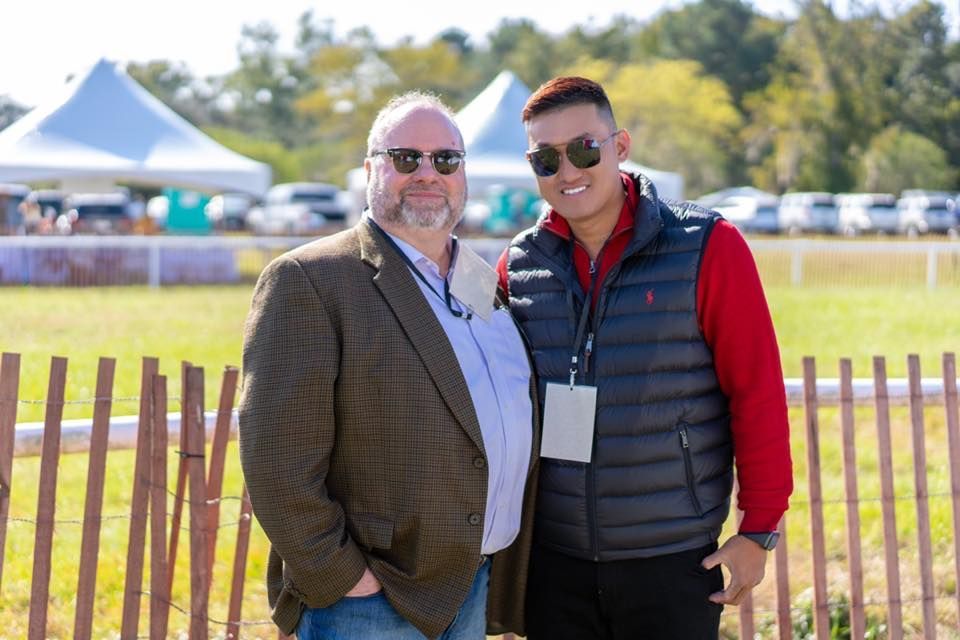 Two men are standing next to each other in a field.