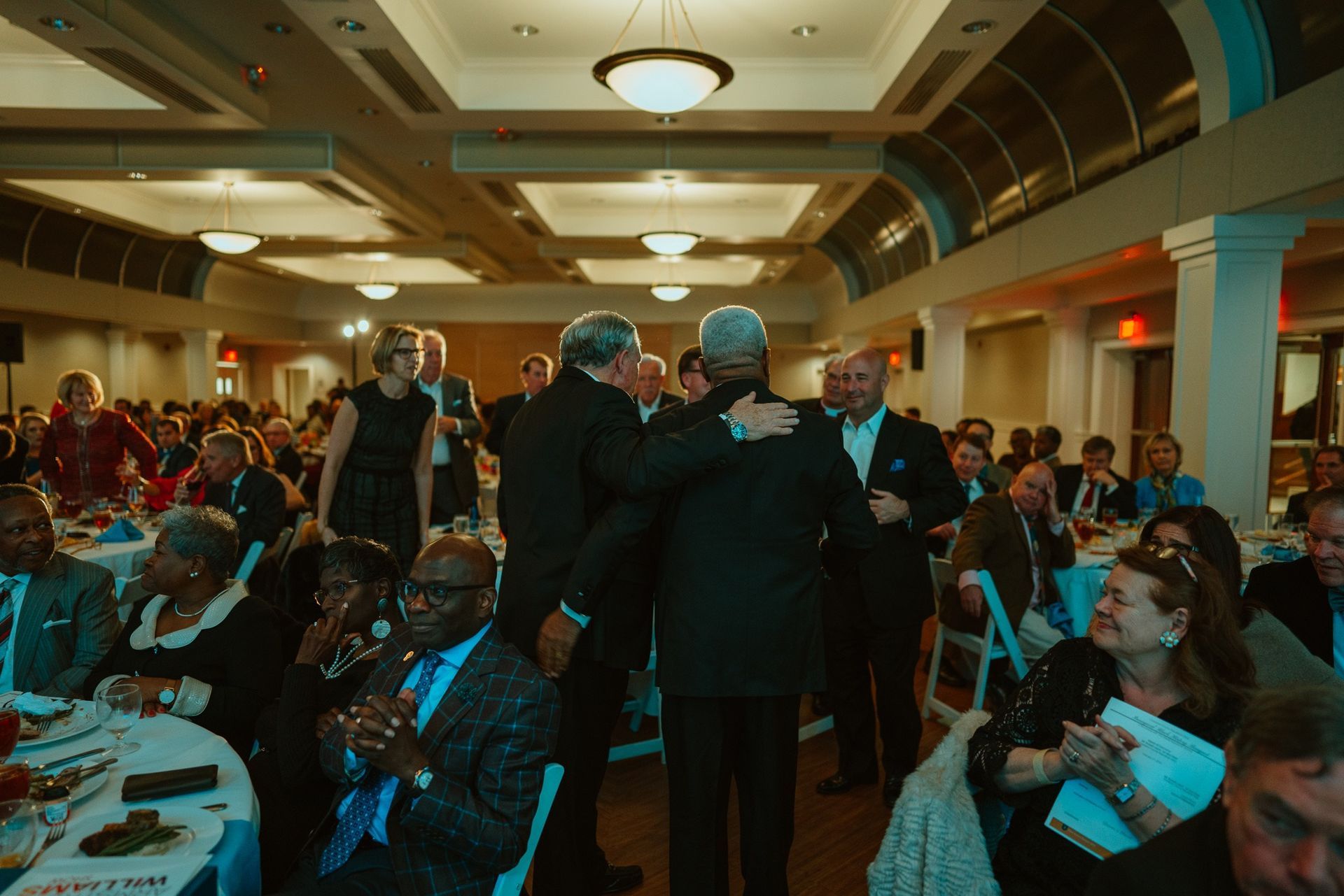 A large group of people are sitting at tables in a large room.