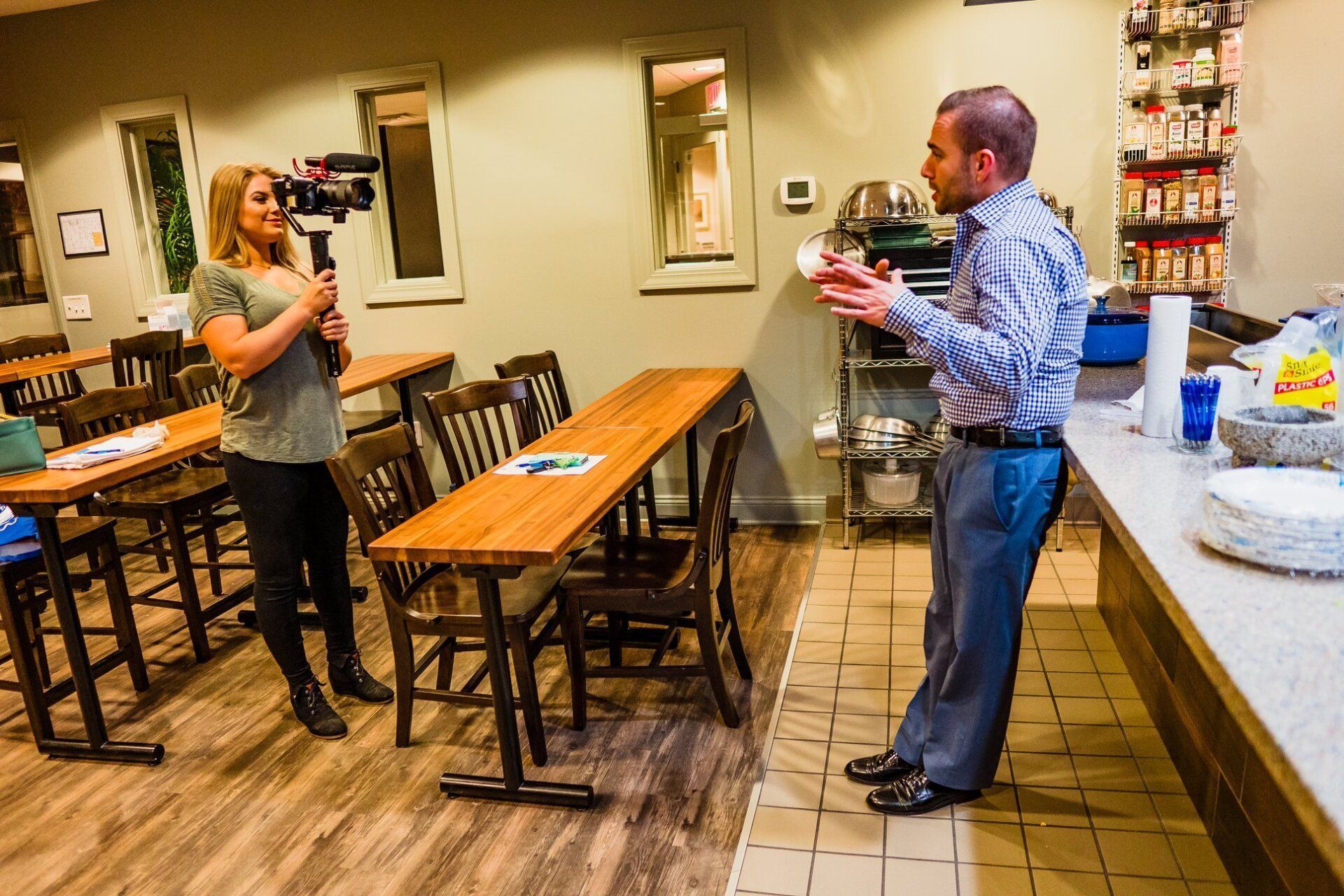 A man and a woman are standing in a room talking to each other.